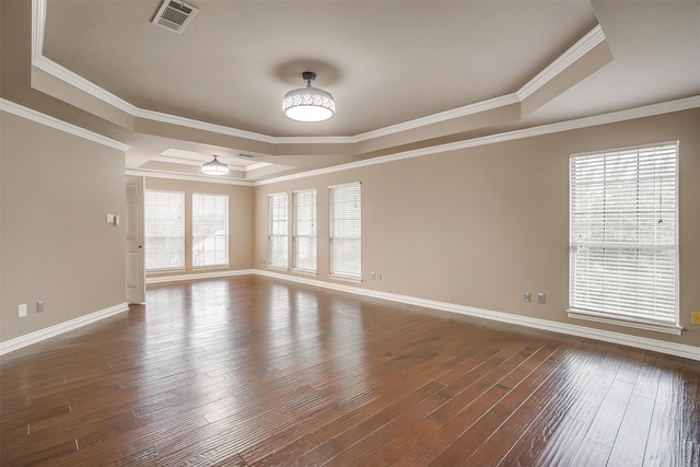 empty room with dark wood-type flooring, a tray ceiling, and a healthy amount of sunlight