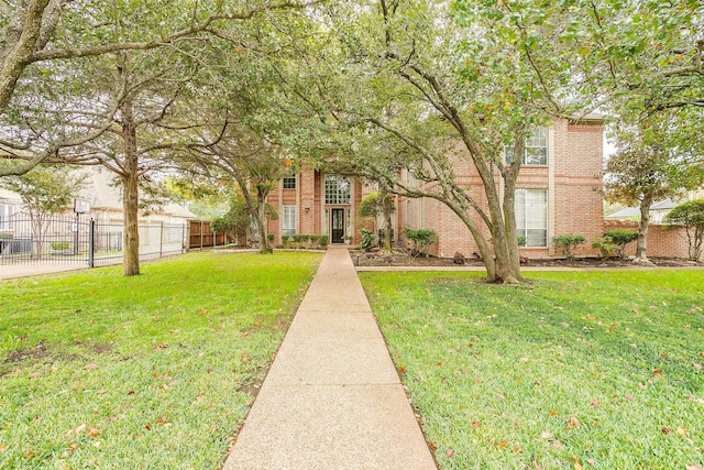 view of front of property featuring fence, a front lawn, and brick siding