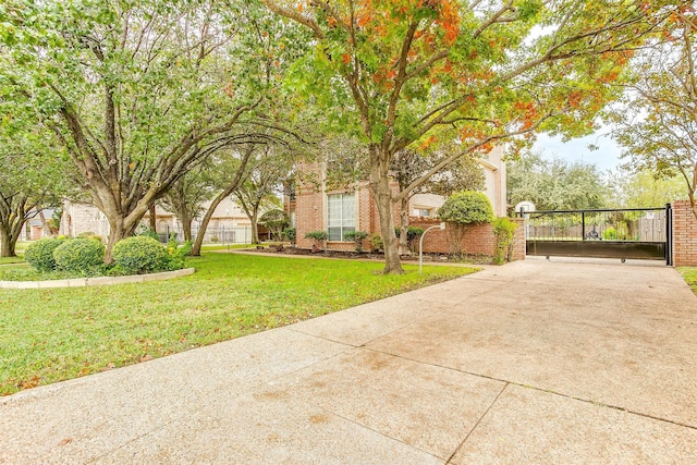 view of front facade with driveway, a front lawn, fence, and a gate