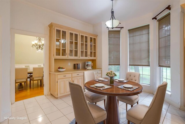 tiled dining space featuring crown molding and a chandelier