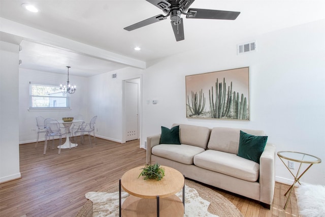 living room featuring beamed ceiling, ceiling fan with notable chandelier, and light hardwood / wood-style flooring