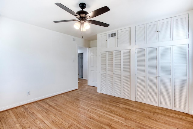 unfurnished bedroom with multiple closets, ceiling fan, and light hardwood / wood-style floors