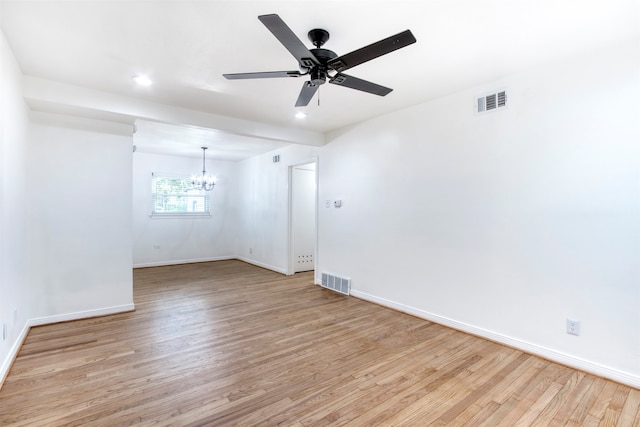 spare room with ceiling fan with notable chandelier and light wood-type flooring