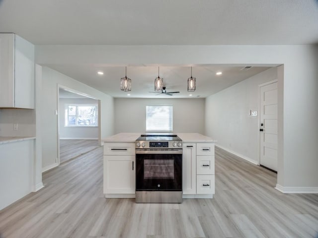 kitchen with a wealth of natural light, stainless steel electric range oven, light wood-type flooring, and white cabinetry