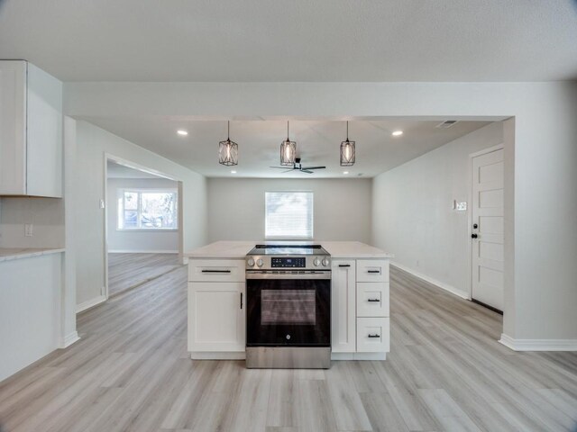 empty room with ceiling fan, a wealth of natural light, and light hardwood / wood-style flooring