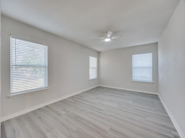 empty room with a ceiling fan, baseboards, and light wood finished floors