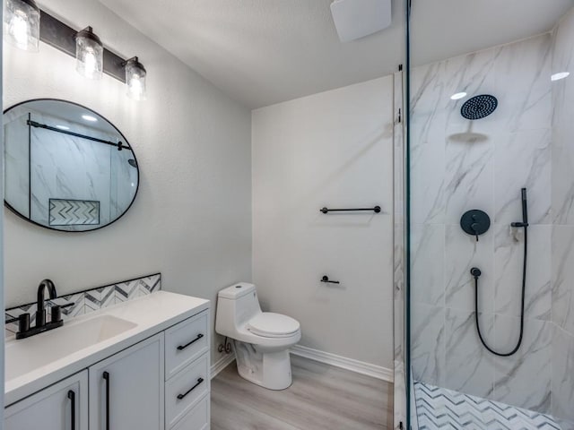 full bathroom with vanity, wood finished floors, baseboards, a marble finish shower, and toilet