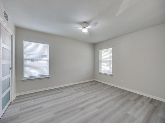 unfurnished room featuring visible vents, a ceiling fan, baseboards, and light wood finished floors