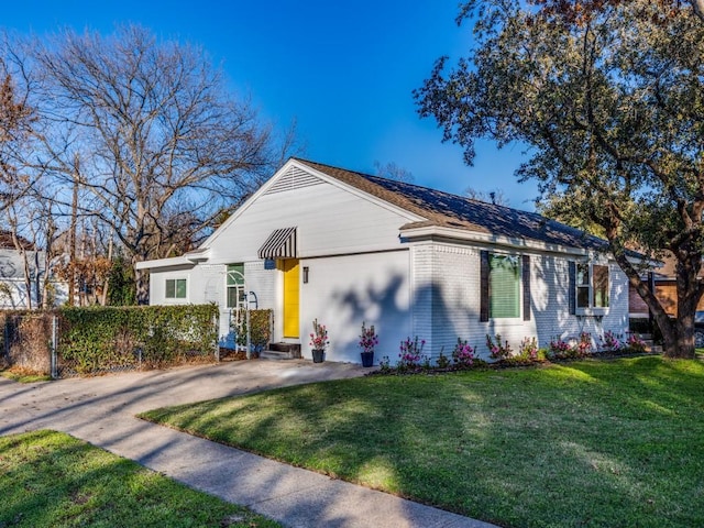 view of front of house featuring a front yard, fence, driveway, entry steps, and brick siding