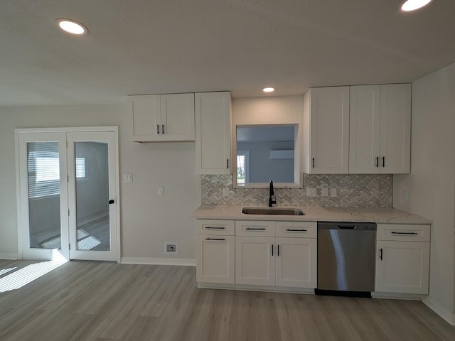 kitchen with a sink, backsplash, dishwasher, and white cabinetry