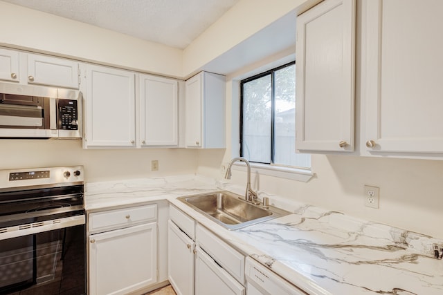 kitchen with white cabinets, sink, stainless steel appliances, and a textured ceiling