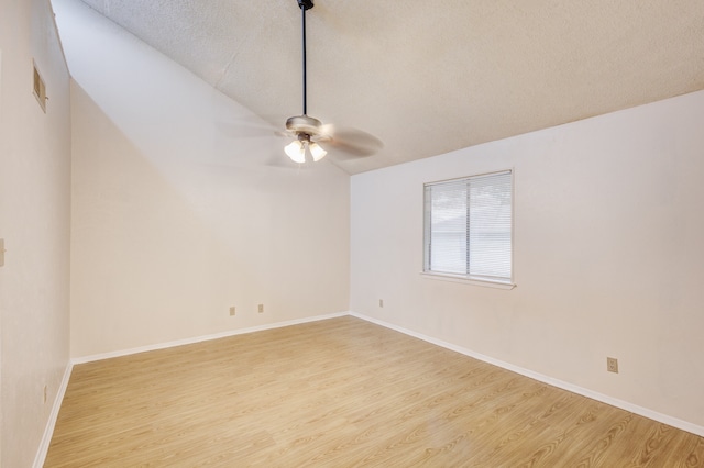 spare room featuring vaulted ceiling, ceiling fan, light hardwood / wood-style flooring, and a textured ceiling