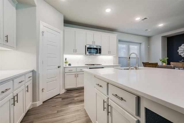 kitchen featuring light wood-style floors, white cabinetry, recessed lighting, appliances with stainless steel finishes, and a sink