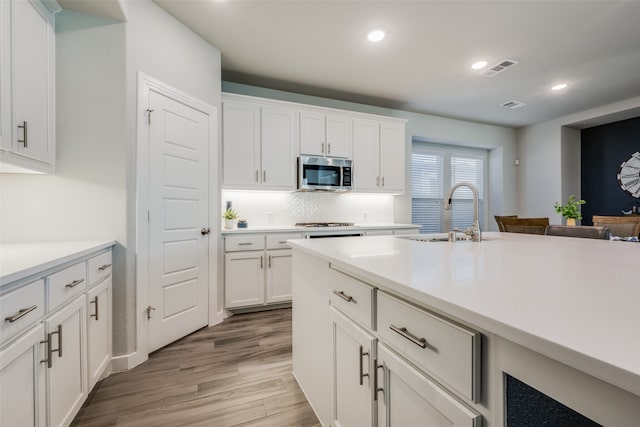 kitchen featuring white cabinets, sink, appliances with stainless steel finishes, and light hardwood / wood-style flooring