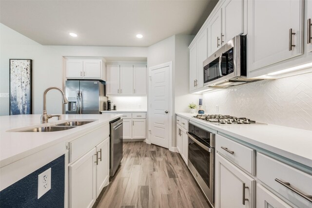 712 8th St, Argyle, TX 76226 - kitchen featuring appliances with stainless steel finishes, a sink, light wood-type flooring, light countertops, and white cabinets