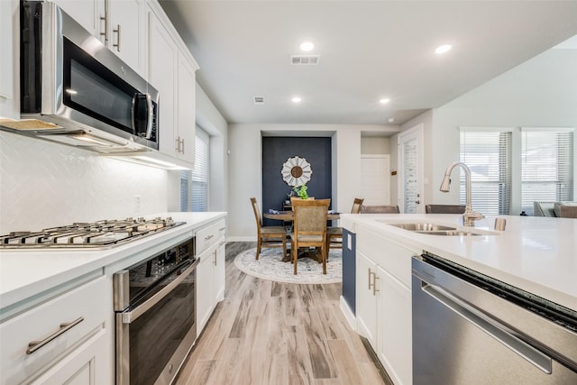 kitchen featuring a sink, light countertops, appliances with stainless steel finishes, and a healthy amount of sunlight