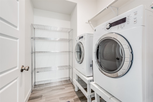 clothes washing area with washer and dryer and light wood-type flooring