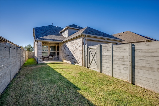 back of house with a lawn and a patio