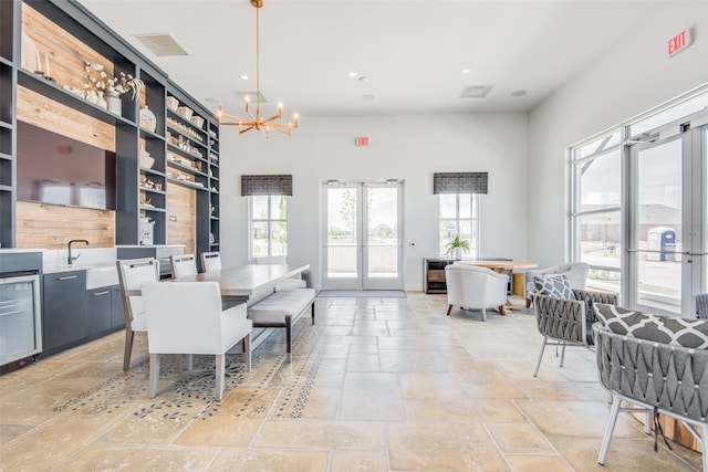 dining room featuring plenty of natural light, beverage cooler, french doors, and an inviting chandelier