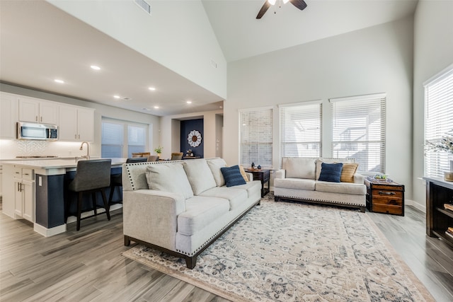 living room featuring light wood-type flooring, high vaulted ceiling, a wealth of natural light, and ceiling fan