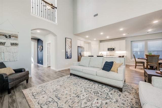 living room featuring a notable chandelier, a high ceiling, and light wood-type flooring