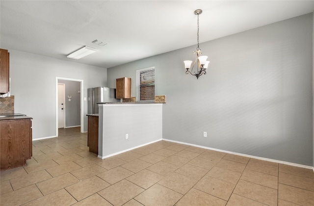 kitchen with pendant lighting, stainless steel fridge, an inviting chandelier, and kitchen peninsula