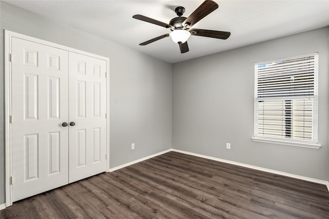 unfurnished bedroom with dark wood-type flooring, ceiling fan, and a closet