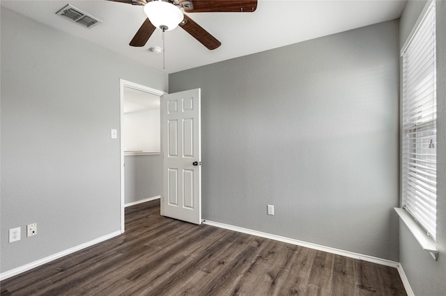 spare room with dark wood-type flooring, a wealth of natural light, and ceiling fan