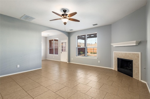 unfurnished living room with a tile fireplace, ceiling fan, and light tile patterned flooring