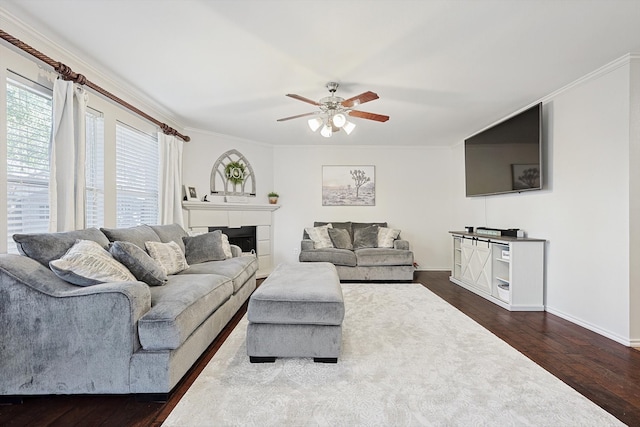 living room with ornamental molding, ceiling fan, and dark wood-type flooring