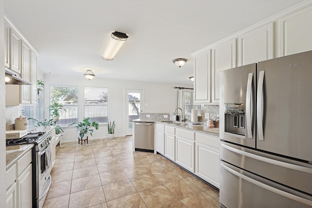 kitchen featuring white cabinets, backsplash, stainless steel appliances, and a healthy amount of sunlight