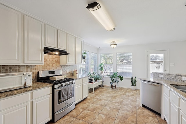 kitchen with appliances with stainless steel finishes, tasteful backsplash, white cabinetry, and a healthy amount of sunlight