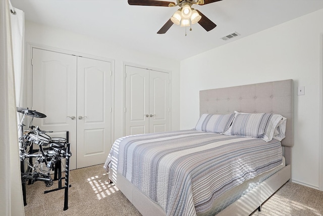 carpeted bedroom with two closets and ceiling fan