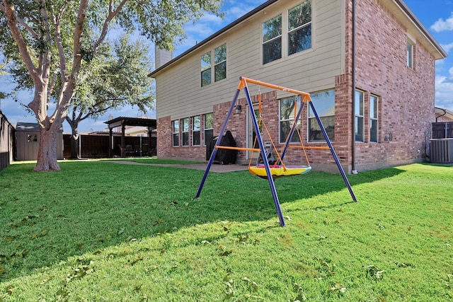 back of house featuring a playground, central AC, a yard, and a shed