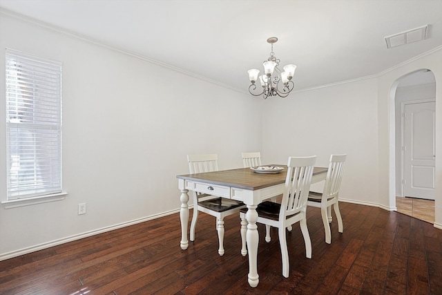 dining room featuring dark hardwood / wood-style floors, crown molding, and an inviting chandelier