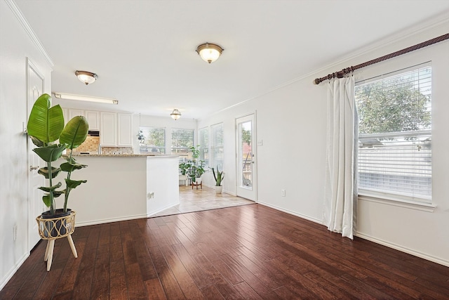 unfurnished living room featuring wood-type flooring, ornamental molding, and a wealth of natural light