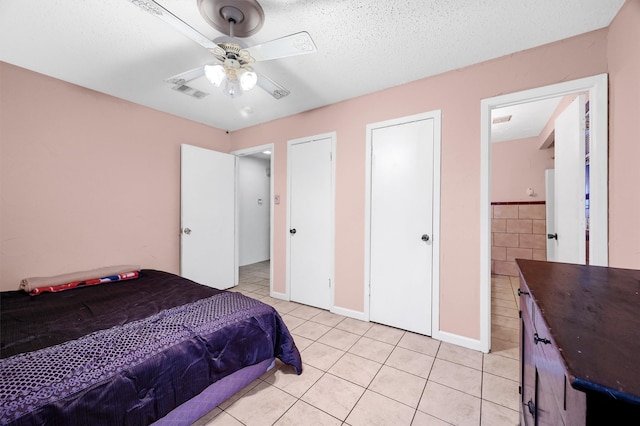 tiled bedroom with ceiling fan and a textured ceiling