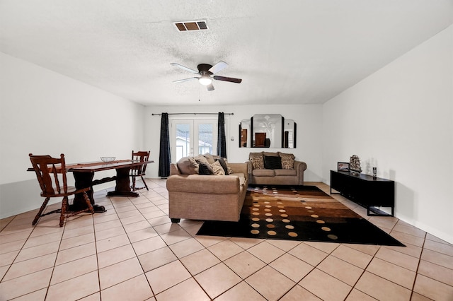 living room featuring ceiling fan, french doors, light tile patterned flooring, and a textured ceiling