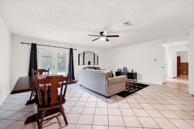 living room with ceiling fan, french doors, light tile patterned floors, and a textured ceiling