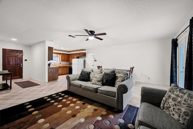 living room with a textured ceiling, ceiling fan, and light tile patterned flooring