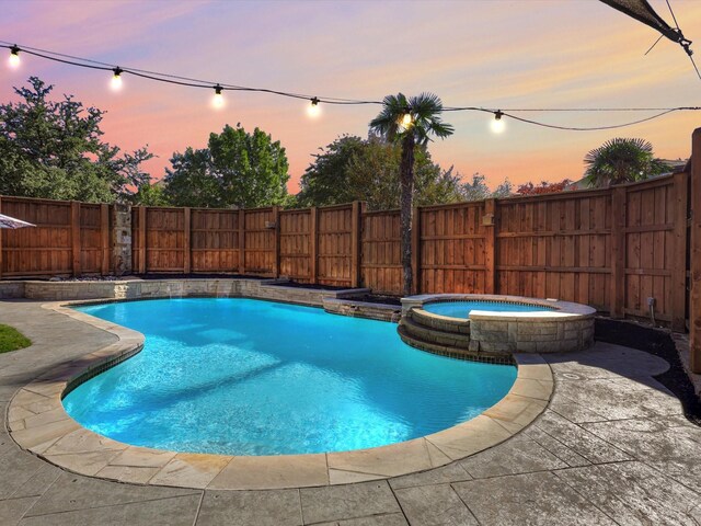 pool at dusk featuring an in ground hot tub and a patio