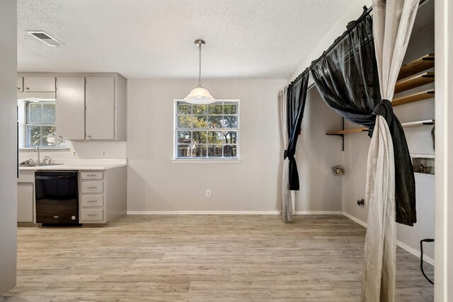 kitchen with sink, hanging light fixtures, gray cabinets, black dishwasher, and light hardwood / wood-style floors