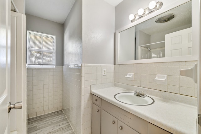 bathroom featuring vanity, wood-type flooring, tile walls, and walk in shower