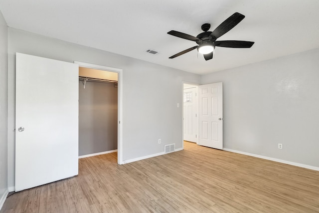 unfurnished bedroom featuring a walk in closet, ceiling fan, a closet, and light wood-type flooring