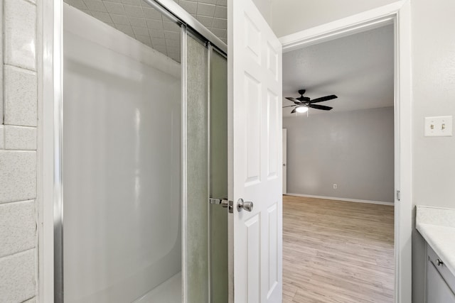 bathroom with hardwood / wood-style floors, vanity, a shower with door, and ceiling fan