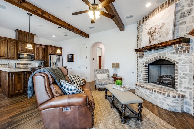 living room with a fireplace, ceiling fan, dark hardwood / wood-style flooring, and beamed ceiling