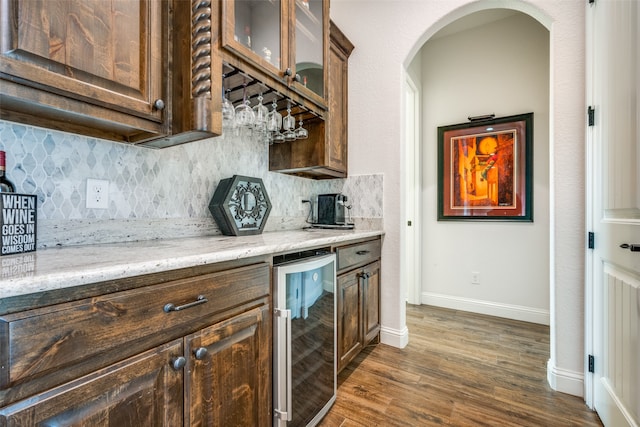 kitchen with backsplash, wine cooler, light stone counters, and dark hardwood / wood-style flooring