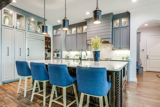 kitchen with decorative light fixtures, gray cabinets, a spacious island, and light hardwood / wood-style flooring