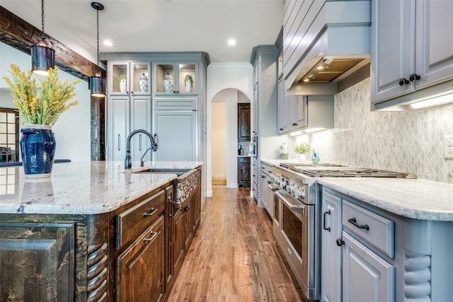 kitchen featuring gray cabinetry, custom exhaust hood, high end stainless steel range oven, and hardwood / wood-style flooring