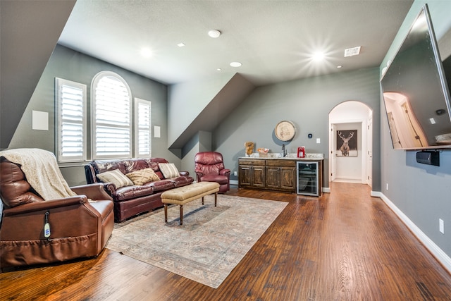 living room with bar area, wine cooler, and dark wood-type flooring